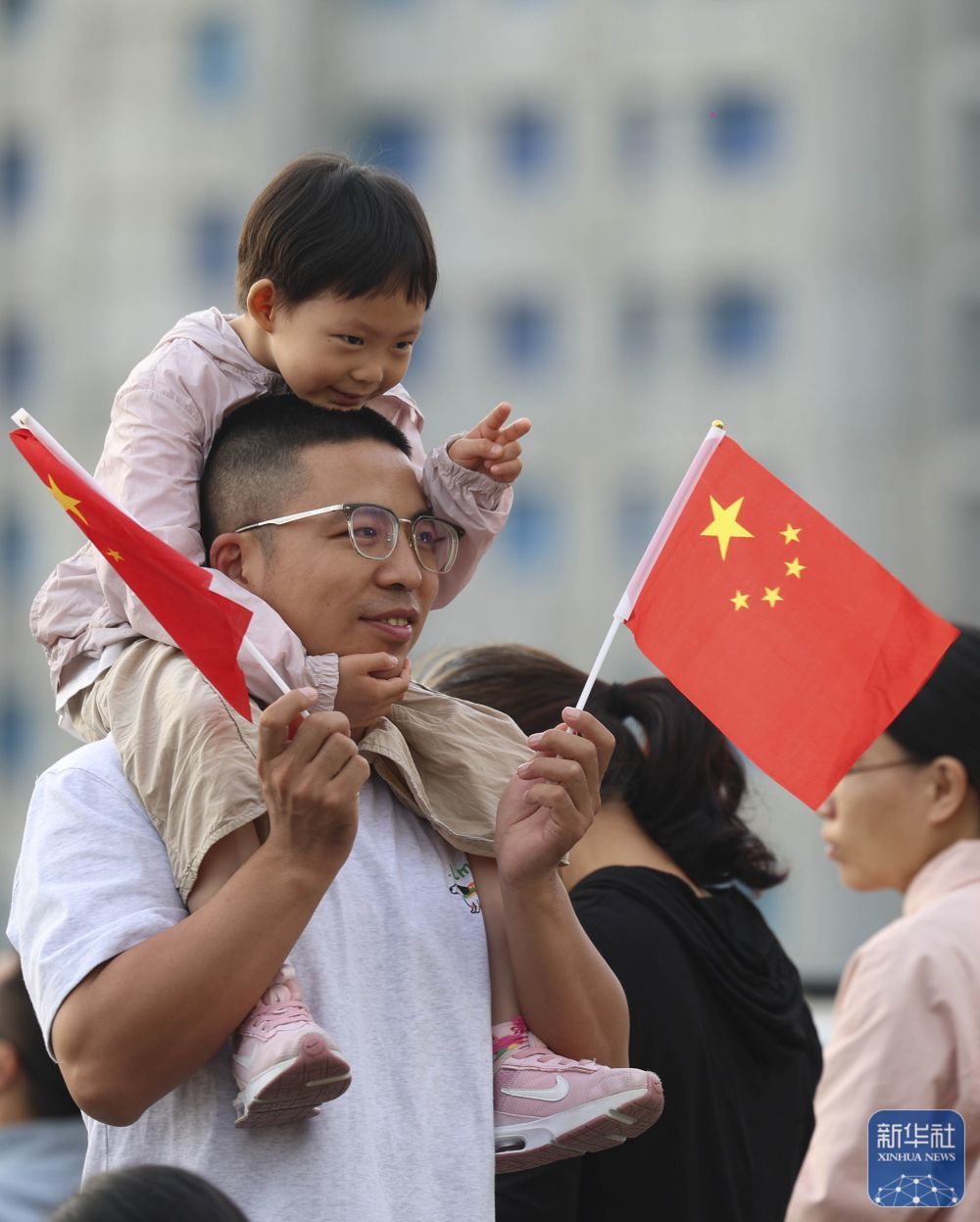↑ 10月1日，在河北省石家庄解放广场，小朋友在家长陪伴下参加升旗仪式。新华社发（梁子栋摄）