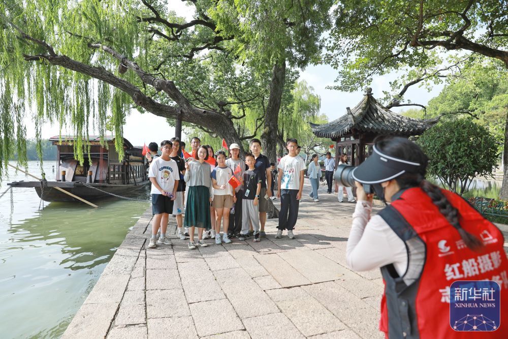↑ 10月1日，在浙江省嘉兴市南湖景区湖心岛，游客与“红船”合影。新华社发（金鹏摄）