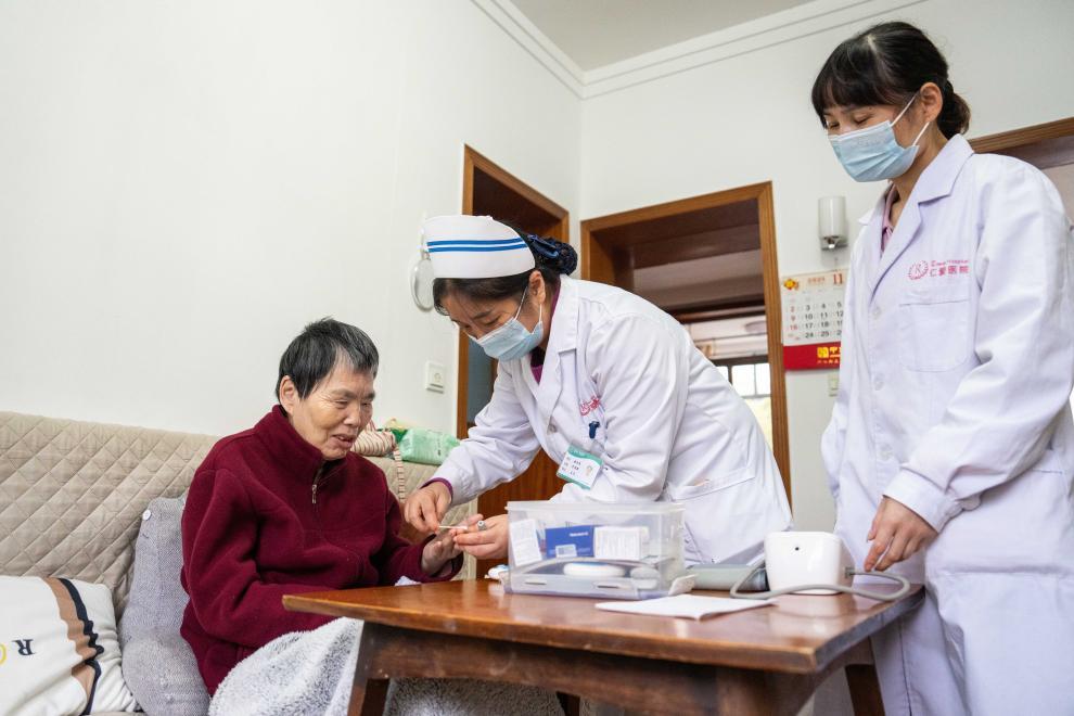 在湖南省长沙市望城区高塘岭街道中南社区,医务人员定期上门为行动不便的居民(左)检查身体。新华社记者 陈思汗 摄