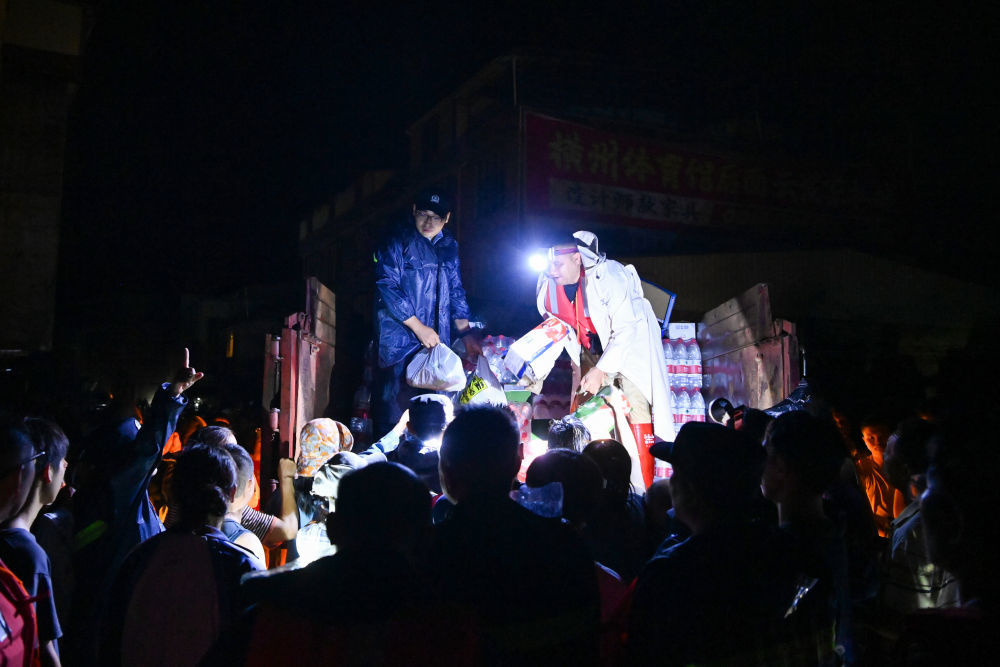 7月6日,在广西南宁横州市校椅镇六蓝村,救援人员在分发物资。新华社记者 曹祎铭 摄