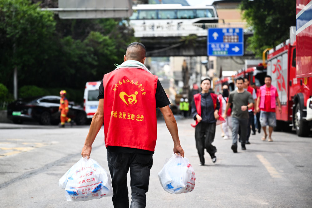 7月19日,志愿者在重庆彭水县崩塌灾害救援现场附近提运物资。新华社记者 王全超 摄
