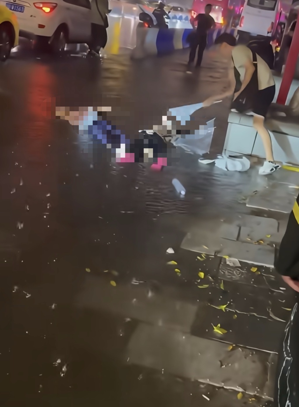 事发现场，一名男子试图用雨伞救援。
