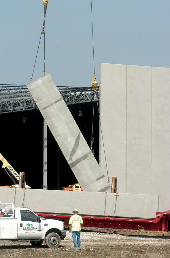 A crane lifts a section of the building's wall.