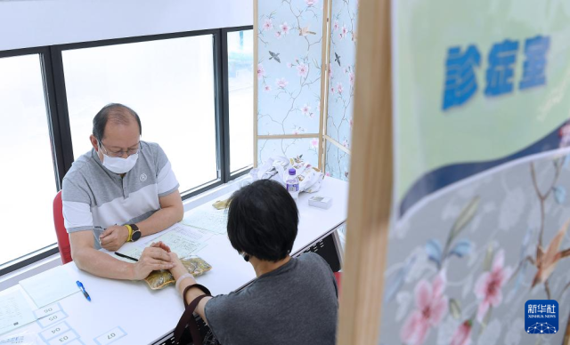4月11日，在荃湾区马湾中医义诊活动中，一名中医师为居民号脉。新华社记者 陈铎 摄