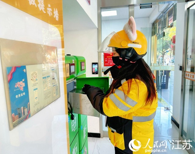 外卖员朱秋华在驿站换电池。人民网 周梦娇摄