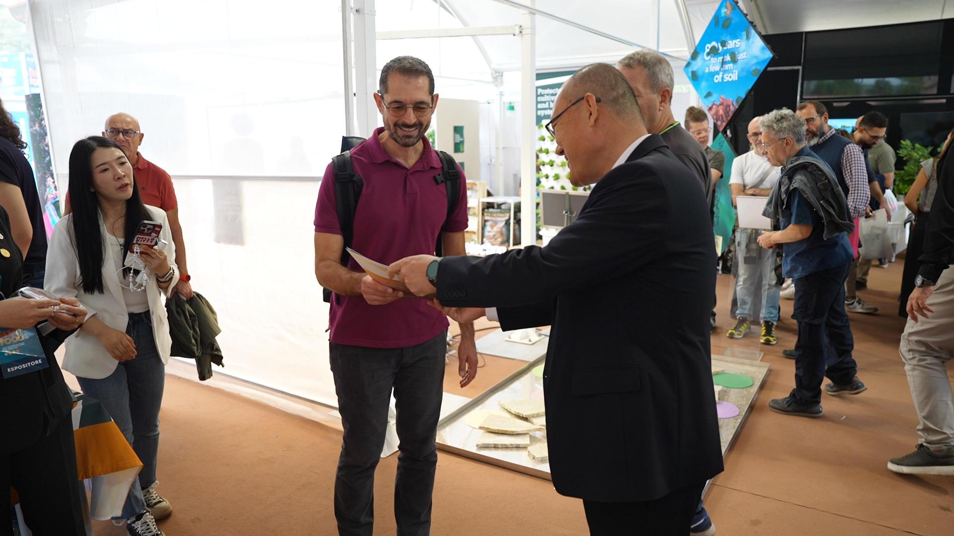 1428503308100240.jpg 5.曹磊向参展者介绍金丰公社.jpg